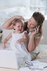 Picture of mom on phone trying to soothe crying toddler